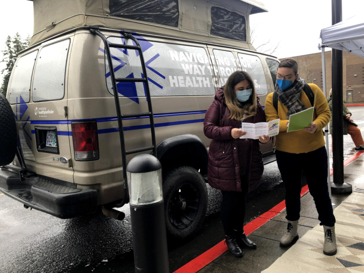 Ana Howe, a navigator with the Washington Healthplanfinder adventure tour, and Mary McHale, Associate Director of Outreach with Washington Healthplanfinder, discuss health insurance options in front of the adventure tour van parked outside of the Vancouver Mall. The adventure tour seeks to enroll more people in state health insurance before the open enrollment period ends on Dec. 15.