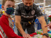 (Photo contributed by the city of Battle Ground
Nineteen kids spent the morning of Dec. 4 at the Battle Ground Walmart shopping for gifts for their families and items for themselves, accompanied by 10 Battle Ground police officers who volunteer for this special Shop with a Cop assignment.)