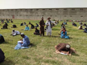 Dr. Mohammad Khan Kharoti, center, observes boys taking grade-level placement exams on the sports field.