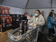 Brett Corpuz of Portland joins a crowd of shoppers as he picks up fireworks ahead of the New Year's holiday at Mean Gene Fireworks in Hazel Dell on Thursday afternoon. It has been about 18 months since vendors could sell fireworks. Although Clark County's interim ordinance is increasing business opportunities for firework stands, vendors are still struggling to make up for previous financial losses.