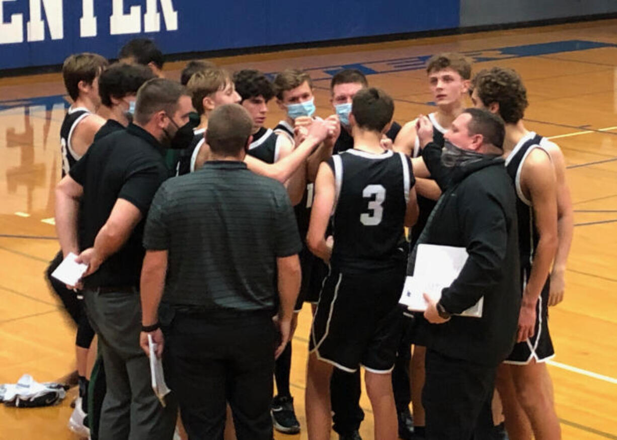 The Woodland boys basketball team gathers for a cheer after beating La Center 55-49 on Wednesday at La Center High School.