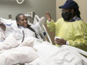 Candice Davis, 30, high-fives her brother, Ali Davis, in her hospital bed at Penn Presbyterian Medical Center in Philadelphia on Nov. 30, 2021. Davis had to have all her limbs partially amputated after a serious bout with COVID-19 in August. Davis has been in high spirits recently, accepting her new reality and journey moving forward.