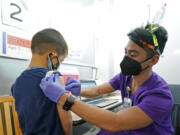 Andre Mattus, right, a nurse at the University of Washington Medical Center, gives the first shot of the Pfizer COVID-19 vaccine to Amar Gunderson, 6 1/2, Tuesday, Nov. 9, 2021, in Seattle. Last week, U.S. health officials gave the final signoff to Pfizer's kid-size COVID-19 shot, a milestone that opened a major expansion of the nation's vaccination campaign to children as young as 5. (AP Photo/Ted S.