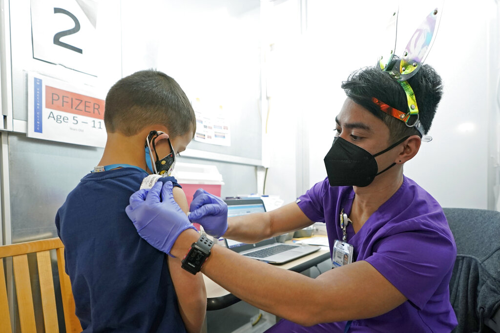 Andre Mattus, right, a nurse at the University of Washington Medical Center, gives the first shot of the Pfizer COVID-19 vaccine to Amar Gunderson, 6 1/2, Tuesday, Nov. 9, 2021, in Seattle. Last week, U.S. health officials gave the final signoff to Pfizer's kid-size COVID-19 shot, a milestone that opened a major expansion of the nation's vaccination campaign to children as young as 5. (AP Photo/Ted S.