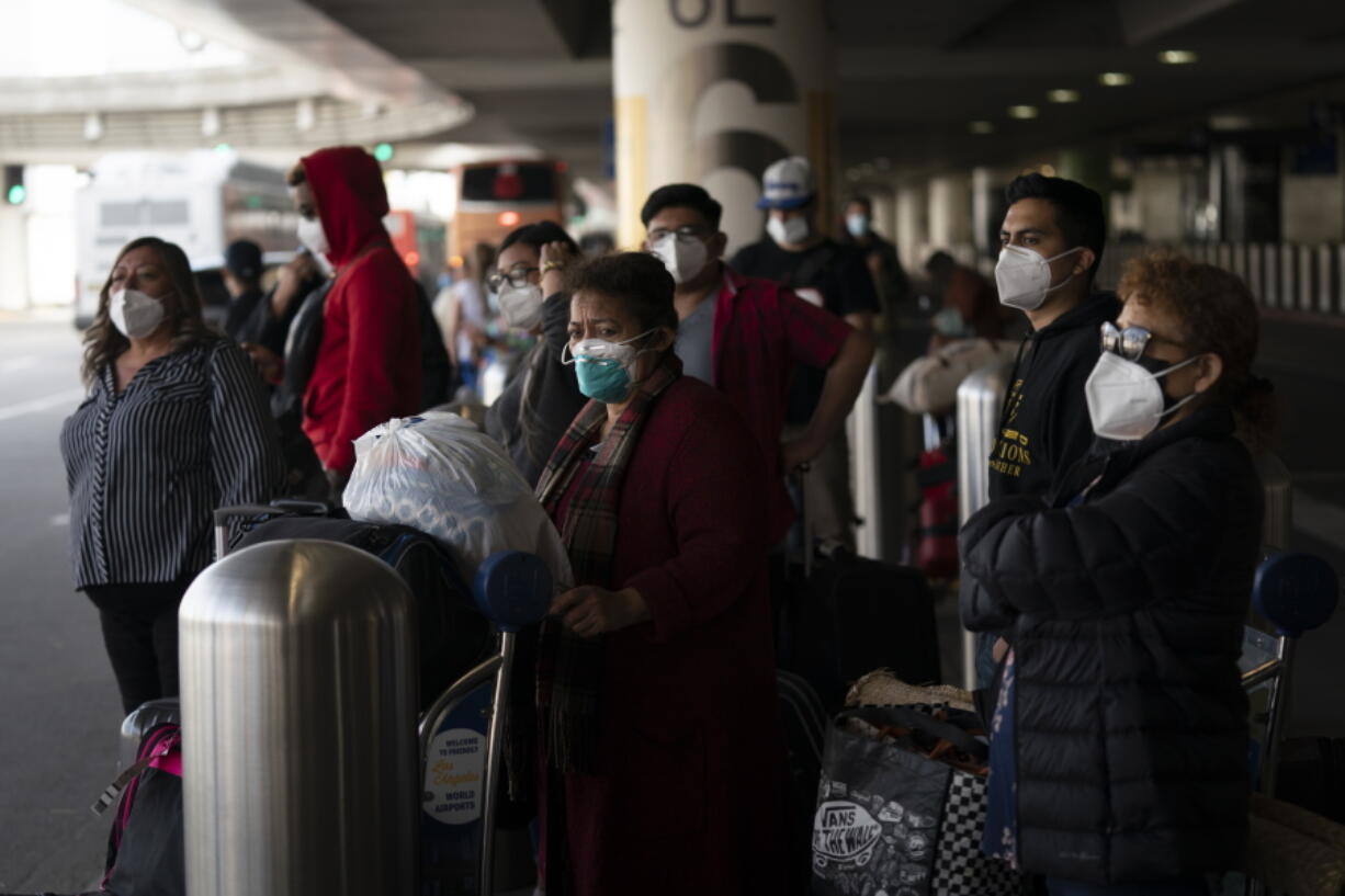 Travelers wait for a shuttle bus to arrive at the Los Angeles International Airport in Los Angeles, on Monday. (Jae C.