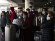 Travelers wait for a shuttle bus to arrive at the Los Angeles International Airport in Los Angeles, on Monday. (Jae C.