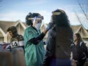 FILE - Maya Goode, a COVID-19 technician, performs a test on Jessica Sanchez outside Asthenis Pharmacy in Providence, R.I., Dec. 7, 2021. As the omicron variant sparks worldwide fears of renewed virus outbreaks, Americans' worries about infection are again on the rise. But fewer say that they are regularly wearing masks or isolating compared with the beginning of the year.