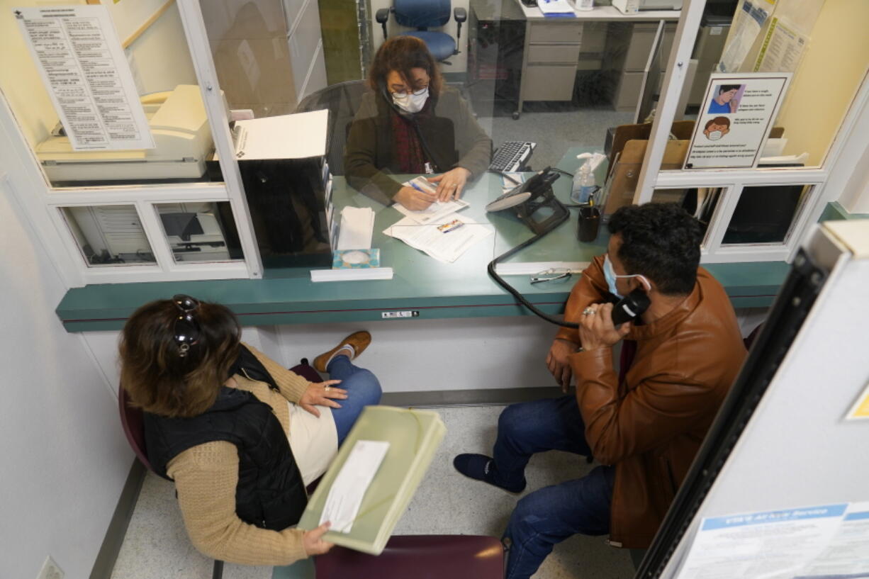 Mohammad Attaie and his wife Deena, newly arrived from Afghanistan, get assistance from medical translator Jahannaz Afshar making a doctor's appointment at the Valley Health Center TB/Refugee Program in San Jose, Calif., on Dec. 9, 2021. The staff of Silicon Valley's decades-old refugee health clinic may not all speak the language of the Afghan refugees starting new lives in the San Francisco Bay Area. But they know the anxiety and stress of newcomers who fled war and chaos to end up in a country where they don't speak the language and everything is different.