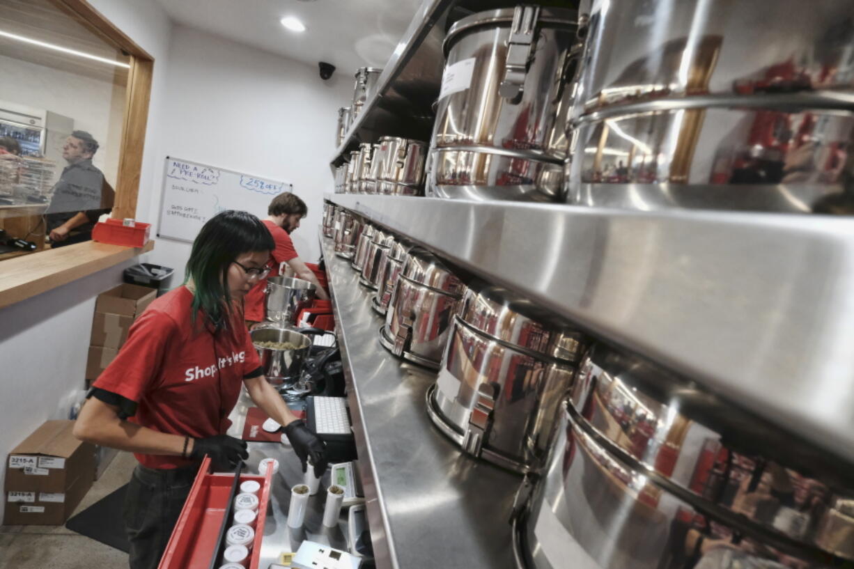 FILE - In this Jan. 12, 2018, file photo, a bud tender prepares marijuana for a customer at Med Men a dispensary in West Hollywood, Calif. Leading California cannabis companies Friday, Dec. 17, 2021, warned Gov. Gavin Newsom that the state's legal industry was on the verge of collapse and needed immediate tax cuts and a rapid expansion of retail outlets to steady the marketplace.