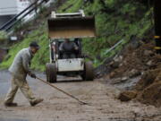 Workers clear a mudslide from a double lot on Westover Drive in Oakland, Calif., on Thursday, Dec. 23, 2021. Heavy overnight rains in Northern California left two people dead in a submerged car as authorities on Thursday urged residents of several Southern California mountain and canyon communities to voluntarily leave their homes because of possible mud and debris flows.