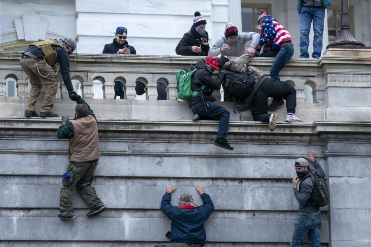 FILE - Insurrections loyal to President Donald Trump climb the west wall of the the U.S. Capitol, Jan. 6, 2021, in Washington.  A federal judge has refused to throw out a key charge against two men accused of storming the U.S. Capitol to obstruct Congress from certifying President Joe Biden's electoral victory. U.S. District Judge Dabney Friedrich ruled on Friday that an obstruction charge applies to the Justice Department's case against Ronald Sandlin and Nathaniel DeGrave.