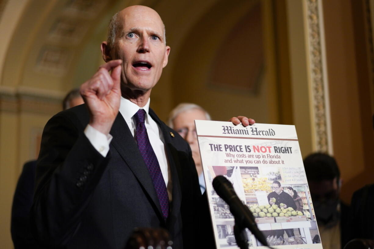 Sen. Rick Scott, R-Fla., holds a printed out copy the Miami Herald newspaper during a news conference after a weekly Republican policy luncheon on Capitol Hill in Washington, Tuesday, Dec.