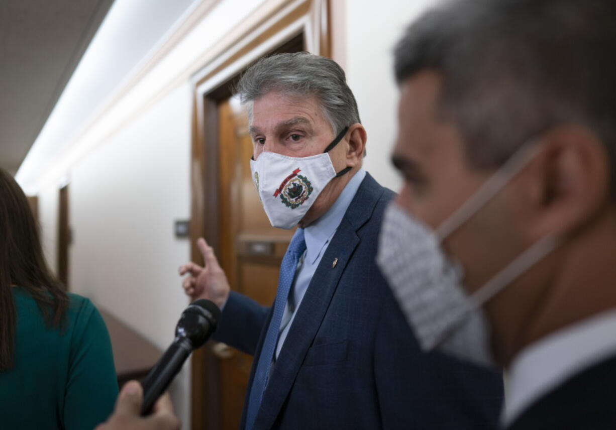 Sen. Joe Manchin, D-W.Va., a key vote on President Joe Biden's domestic spending agenda, tells reporters he's late for a hearing and can't talk, at the Capitol in Washington, Thursday, Dec. 2, 2021. Manchin seems poised to force removal of the bill's four weeks of paid annual leave, a $200 billion item prized by progressives. (AP Photo/J.