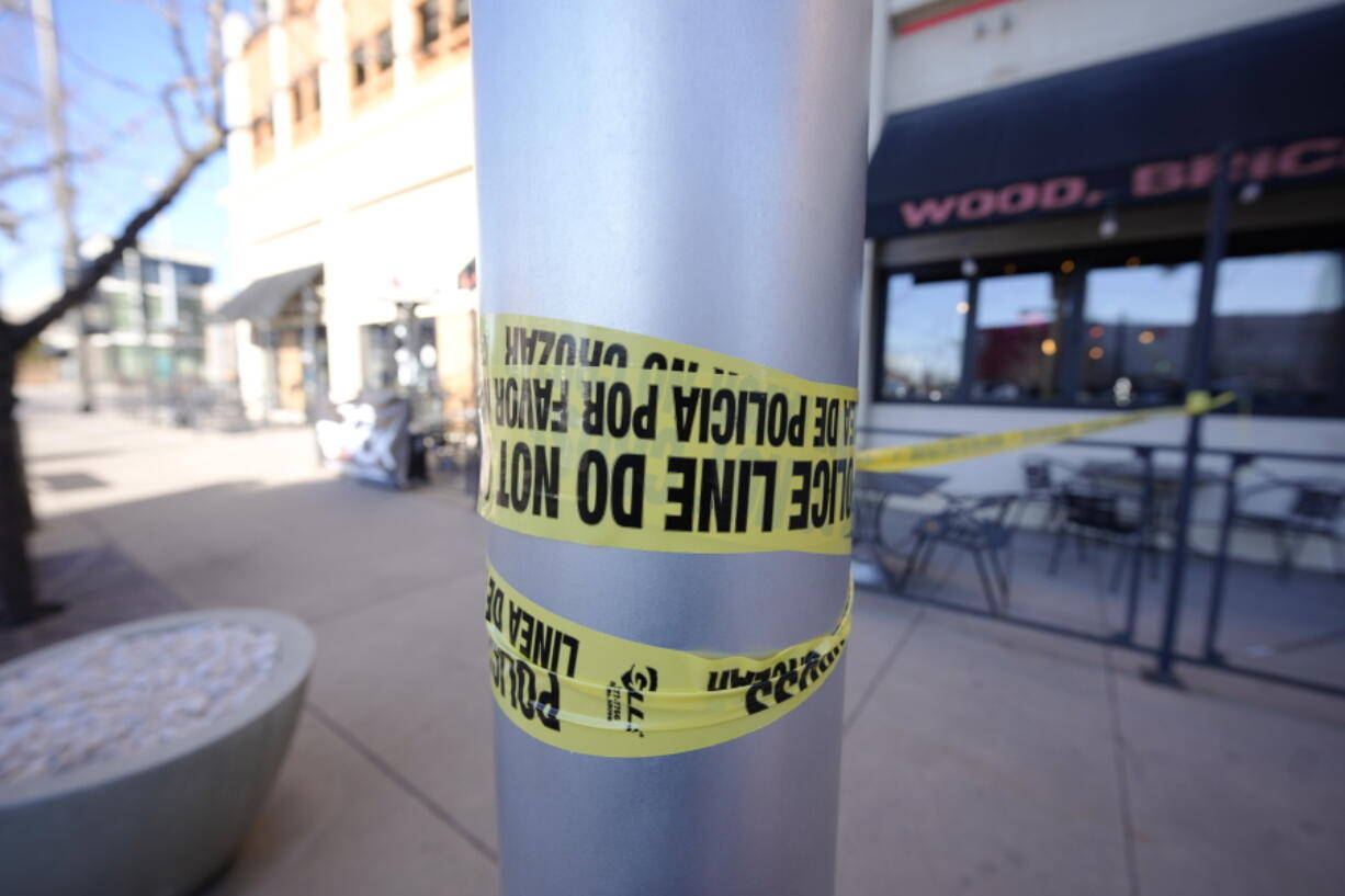 Leftover police tape is wrapped around a pole to block off the sidewalk by a pizza parlor Tuesday, Dec. 28, 2021 in Lakewood, Colo., near one of the scenes of a shooting spree that left five people dead--including the suspected shooter Monday evening--and left three more people wounded. The spree spread from the core of Denver to the western suburb of Lakewood where the suspect was shot and killed by police near a busy intersection in a bustling shopping district.