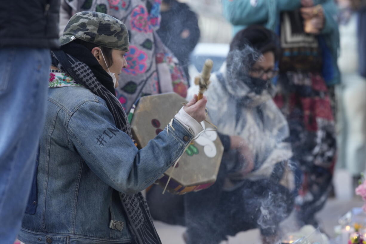 Mourners perform a ritual as they gather outside the door of a tattoo parlor along South Broadway, Tuesday, Dec. 28, 2021, in Denver, one of the scenes of a shooting spree that left six people dead--including the suspected shooter Monday evening--and left two more people wounded. The spree spread from the core of Denver to the western suburb of Lakewood where the suspect was shot and killed by police near a busy intersection in a bustling shopping district.