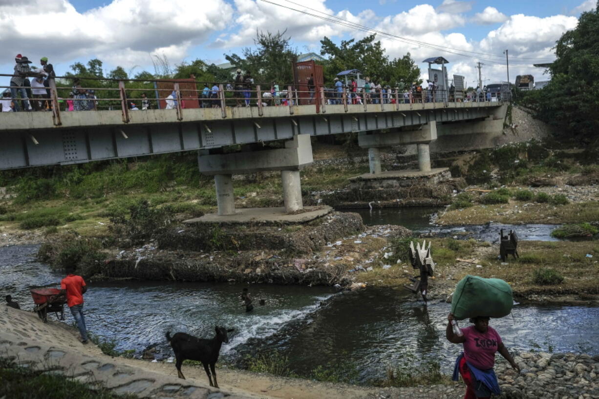 Men bathe in the Massacre River on the border between Dominican Republic and Haiti, in Ouanaminthe, Dominican Republic, Friday, Nov. 19, 2021. As the rest of the world closes its doors to Haitian migrants, the country that shares an island with Haiti also is cracking down in a way that human rights activists say hasn't been seen in decades.