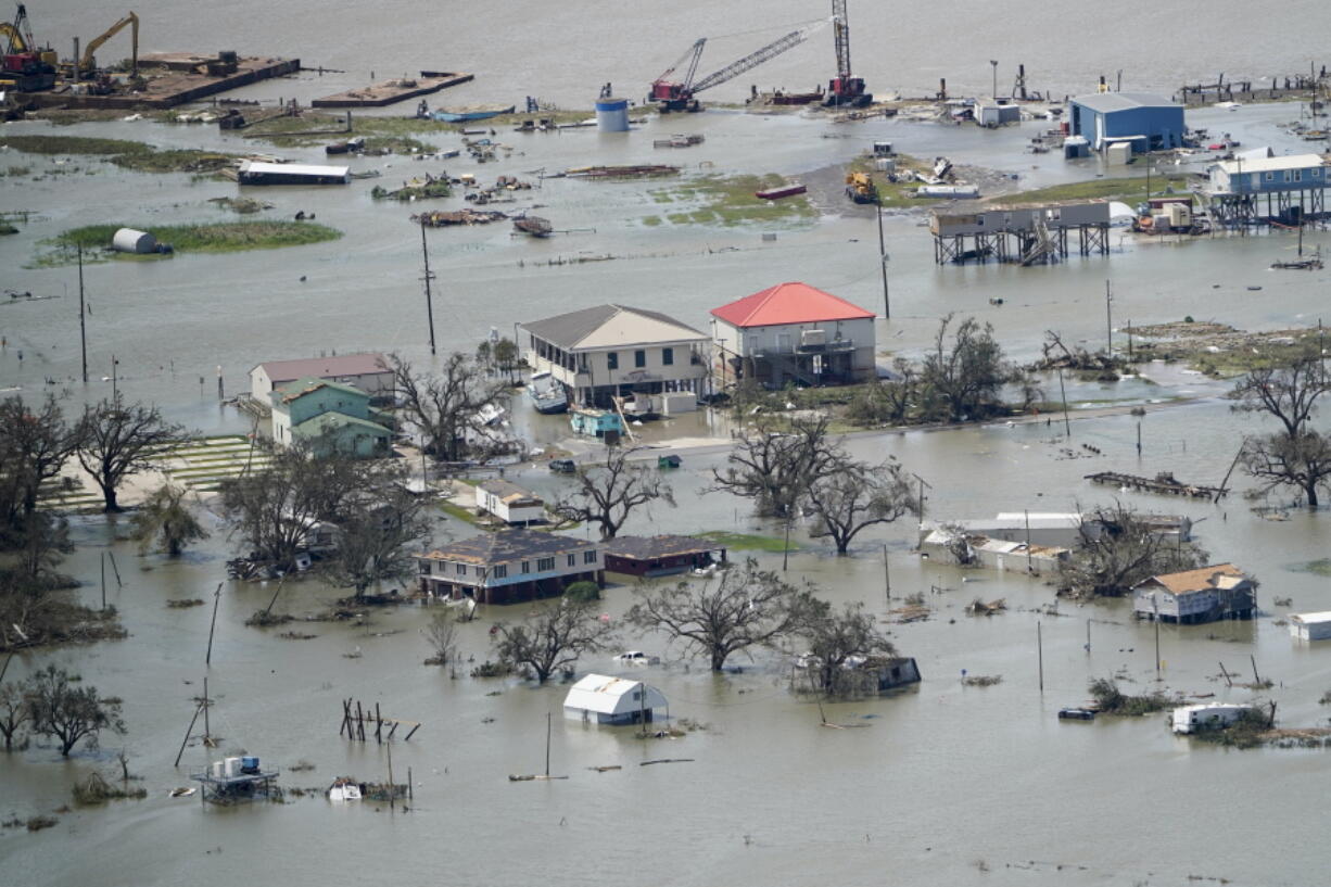 FILE - Buildings and homes are flooded in the aftermath of Hurricane Laura Thursday, Aug. 27, 2020, near Lake Charles, La. In the past year, the southwestern Louisiana city of Lake Charles weathered two hurricanes, intense rainfall that sent water gushing down streets and a deep freeze that burst pipes. Under a revamped federal flood insurance program rolled out in the fall of 2021, millions of homeowners are set for rate hikes that officials say more accurately reflect a property's risk. (AP Photo/David J.