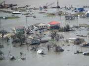 FILE - Buildings and homes are flooded in the aftermath of Hurricane Laura Thursday, Aug. 27, 2020, near Lake Charles, La. In the past year, the southwestern Louisiana city of Lake Charles weathered two hurricanes, intense rainfall that sent water gushing down streets and a deep freeze that burst pipes. Under a revamped federal flood insurance program rolled out in the fall of 2021, millions of homeowners are set for rate hikes that officials say more accurately reflect a property's risk. (AP Photo/David J.