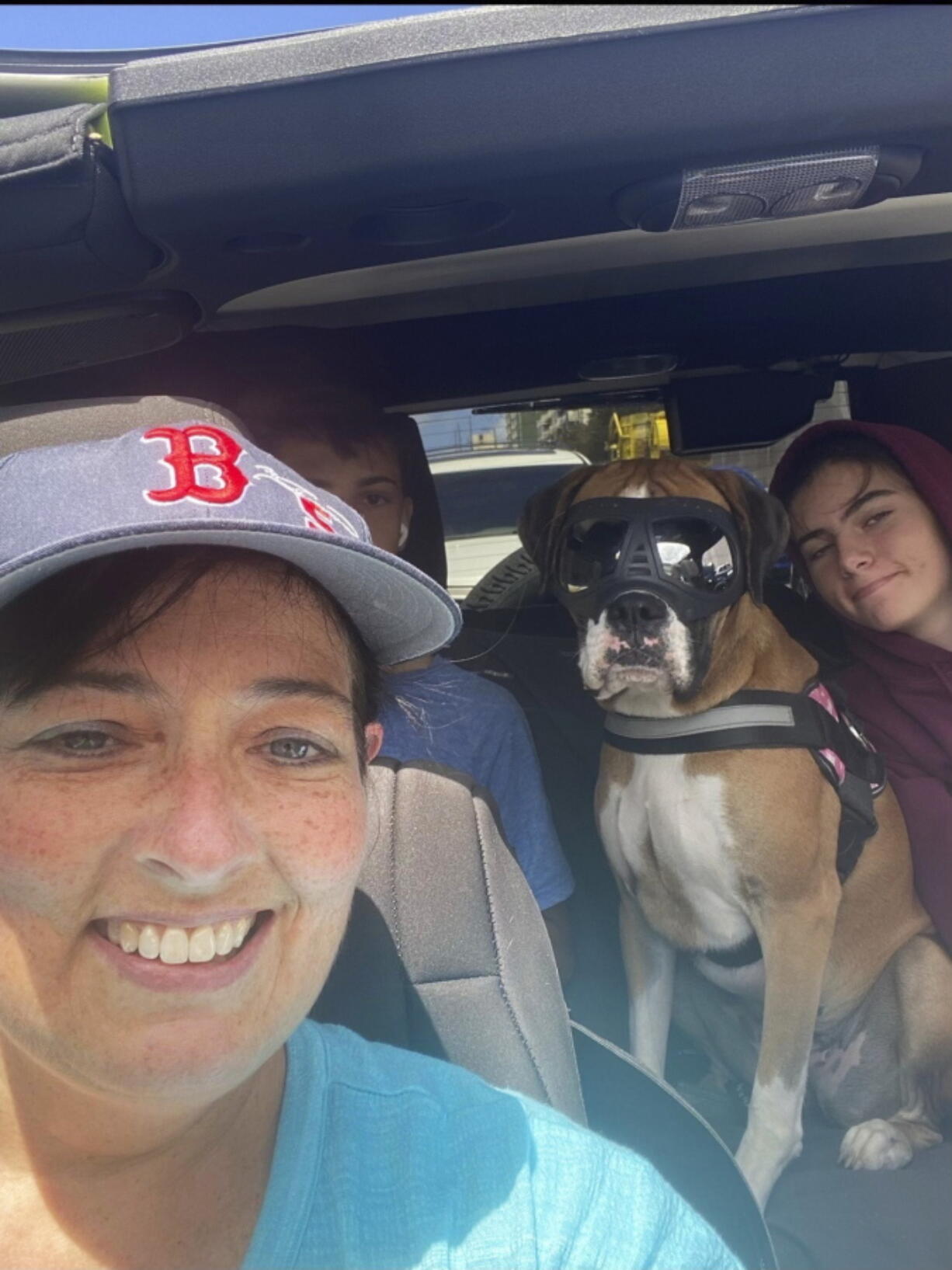 This 2021 photo provided by Cheri Burness shows Burness and her family, including dog Lilikoi, in car in Honolulu.