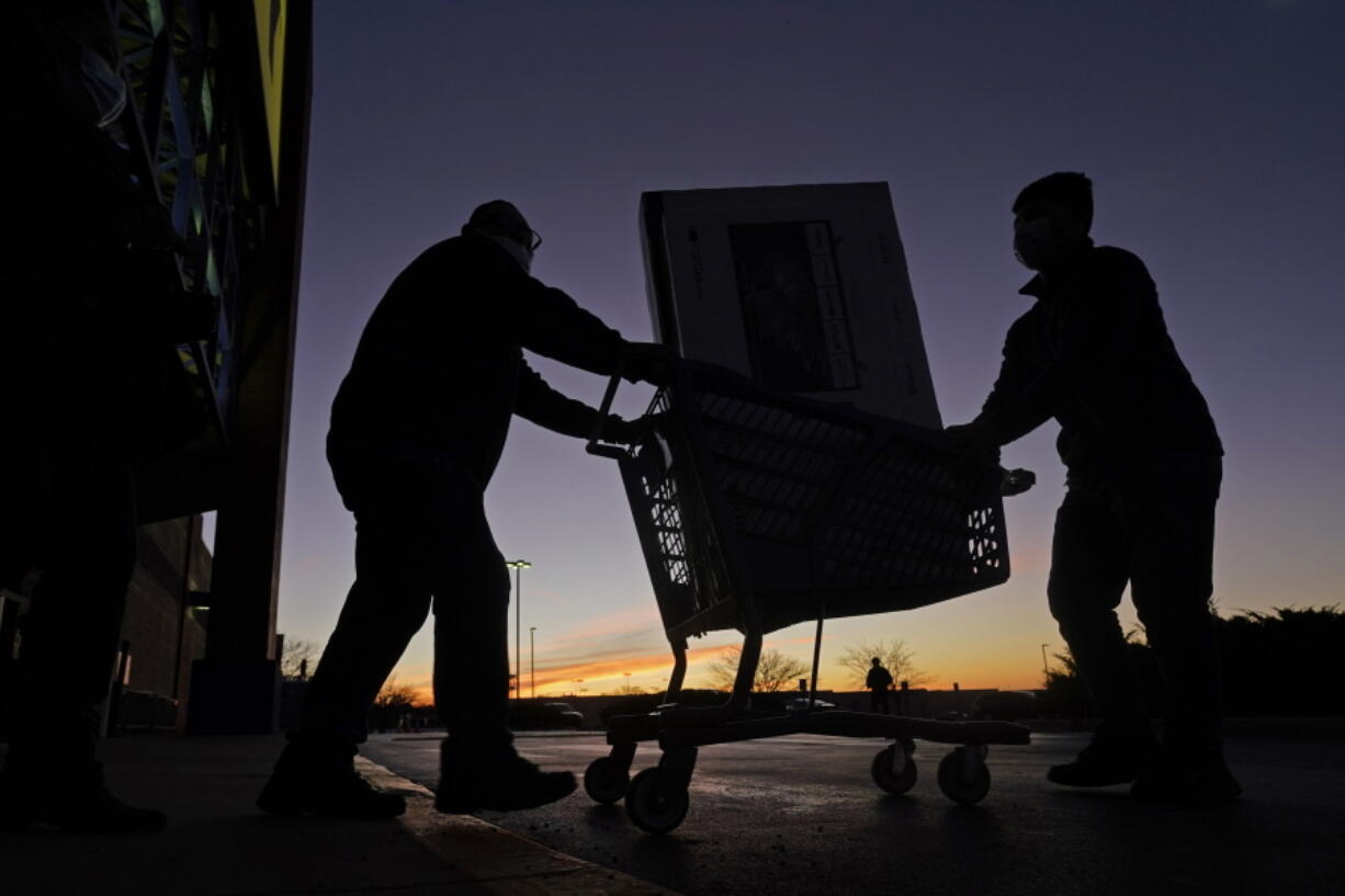 FILE - People transport a television to their car after shopping during a Black Friday sale at a Best Buy store Nov. 26, 2021, in Overland Park, Kan. Retailers overall are expecting record-breaking sales for the holiday shopping season, but low-income customers are struggling as they bear the brunt of the highest inflation in 39 years.