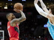 Portland Trail Blazers guard Damian Lillard, left, shoots over Charlotte Hornets guard LaMelo Ball during the second half of an NBA basketball game in Portland, Ore., Friday, Dec. 17, 2021.