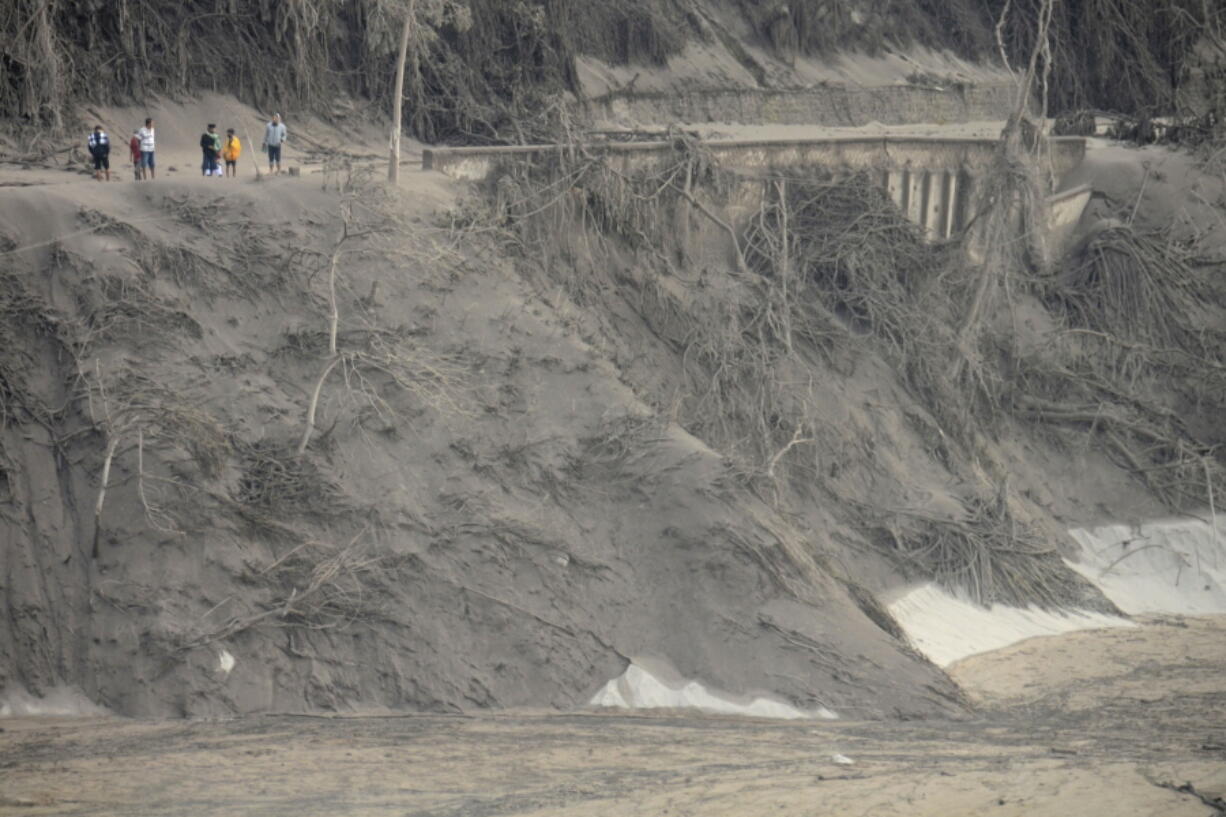 Villagers look at the broken bridge destroyed by the lava flow following the eruption of Mount Semeru in Lumajang district, East Java province, Indonesia, Sunday, Dec. 5, 2021. The death toll from the eruption of the highest volcano on Indonesia's most populous island of Java has risen by a score of still missing, officials said Sunday as rain continued to lash the area and hamper the search.