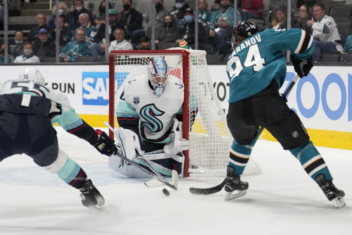 Seattle Kraken goaltender Chris Driedger (60) blocks a goal attempt against San Jose Sharks left wing Alexander Barabanov (94) as Jeremy Lauzon (55) defends during the first period of an NHL hockey game Tuesday, Dec. 14, 2021, in San Jose, Calif.