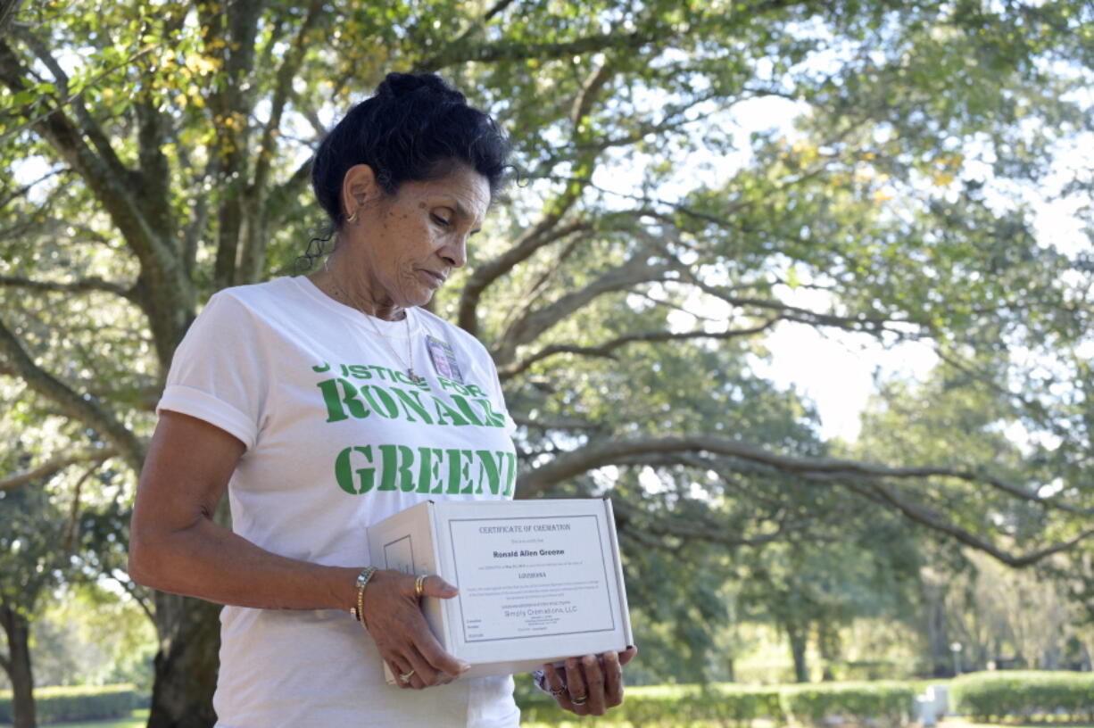 Mona Hardin holds the boxed ashes of her son, Ronald Greene, Saturday, Dec. 4, 2021, in Orlando, Fla. Hardin is haunted by the body-camera images of her son being punched, stunned and dragged by Louisiana State Police. She holds tightly to her son's cremated remains and says she won't be able to put him to rest until she gets justice. After a more than two-year federal probe, still none of the officers involved has been charged. (AP Photo/Phelan M.