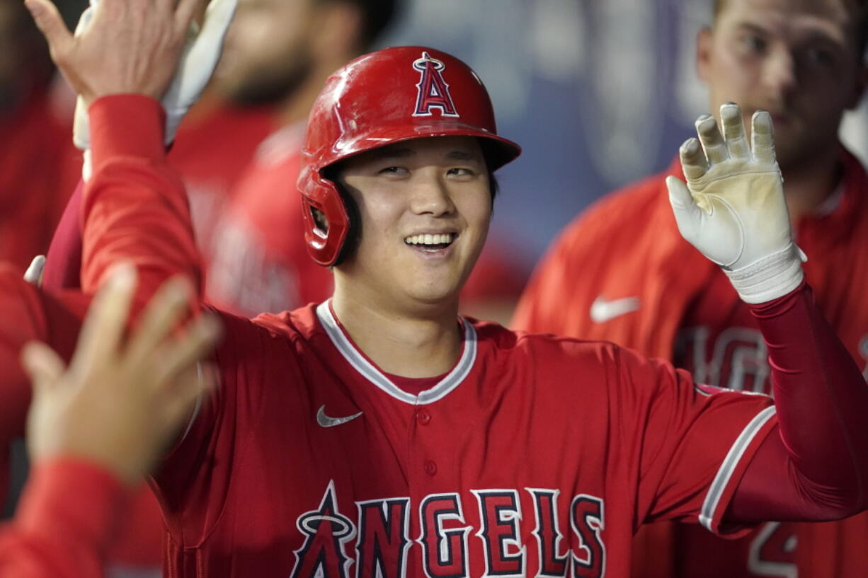 FILE - Los Angeles Angels' Shohei Ohtani is greeted in the dugout after he hit a solo home run during the first inning of a baseball game against the Seattle Mariners, Sunday, Oct. 3, 2021, in Seattle. Ohtani, the Los Angeles Angels' two-way superstar, is the winner of The Associated Press' Male Athlete of the Year award. (AP Photo/Ted S.