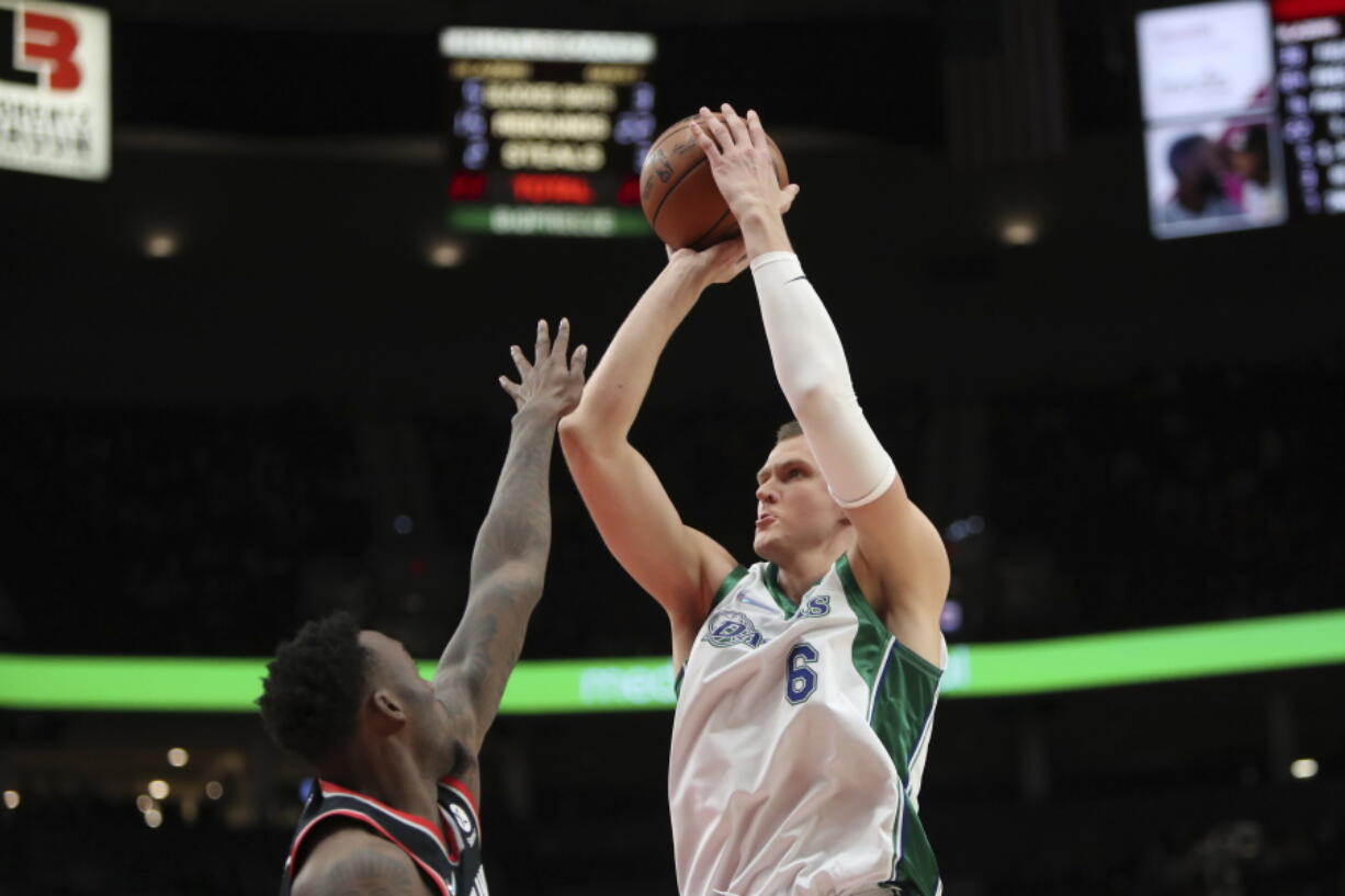 Dallas Mavericks center Kristaps Porzingis shoots over Portland Trail Blazers forward Nassir Little during the second half of an NBA basketball game in Portland, Ore., Monday, Dec. 27, 2021.