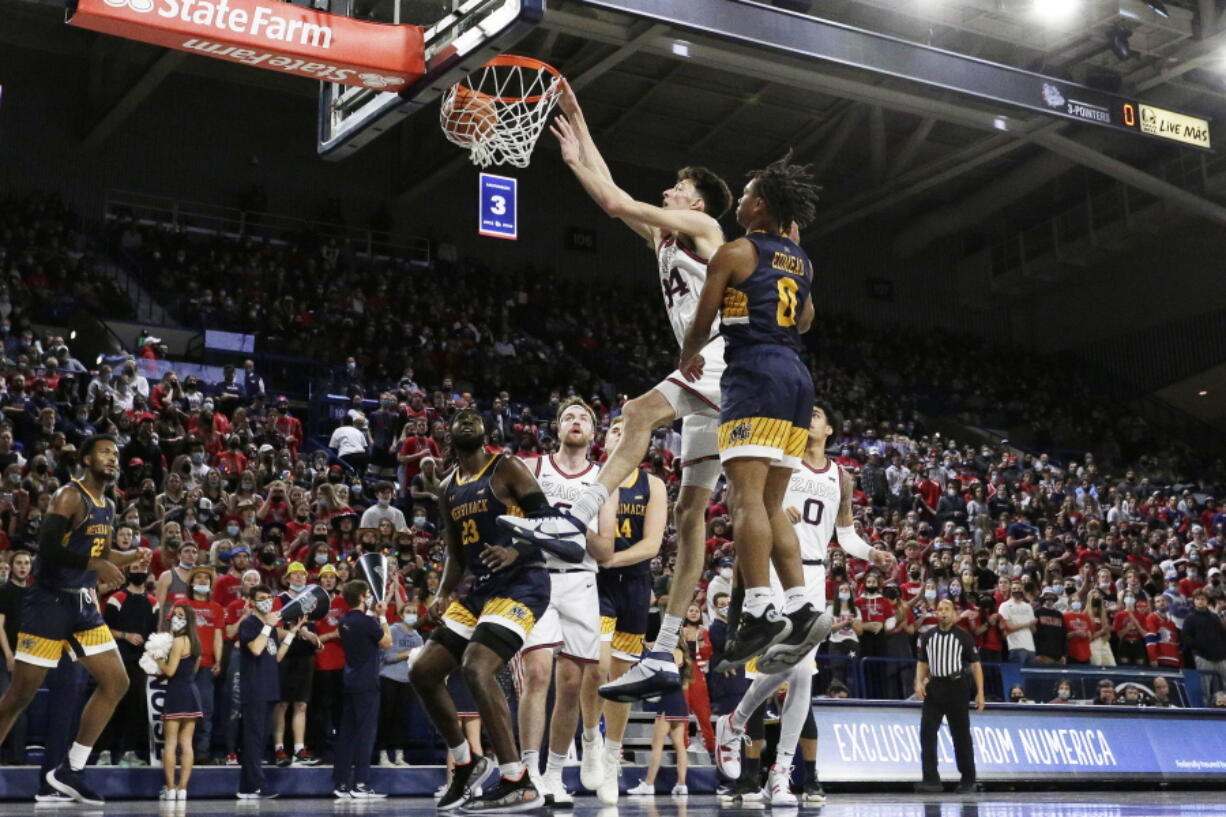 Gonzaga center Chet Holmgren, center left, dunks next to Merrimack guard Malik Edmead during the first half of an NCAA college basketball game, Thursday, Dec. 9, 2021, in Spokane, Wash.