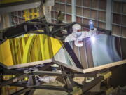 In this Sept. 29, 2014 photo made available by NASA, James Webb Space Telescope Optical Engineer Larkin Carey examines two test mirror segments on a prototype at the Goddard Space Flight Center's giant clean room in Greenbelt, Md. Webb will attempt to look back in time 13.7 billion years, a mere 100 million years after the universe-forming Big Bang as the original stars were forming.