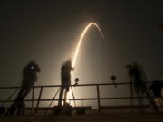 Photographers follow a SpaceX Falcon 9 rocket during a time exposure as it lifts off from Launch Complex 39A at the Kennedy Space Center in Cape Canaveral, Fla., Thursday, Dec. 9, 2021.