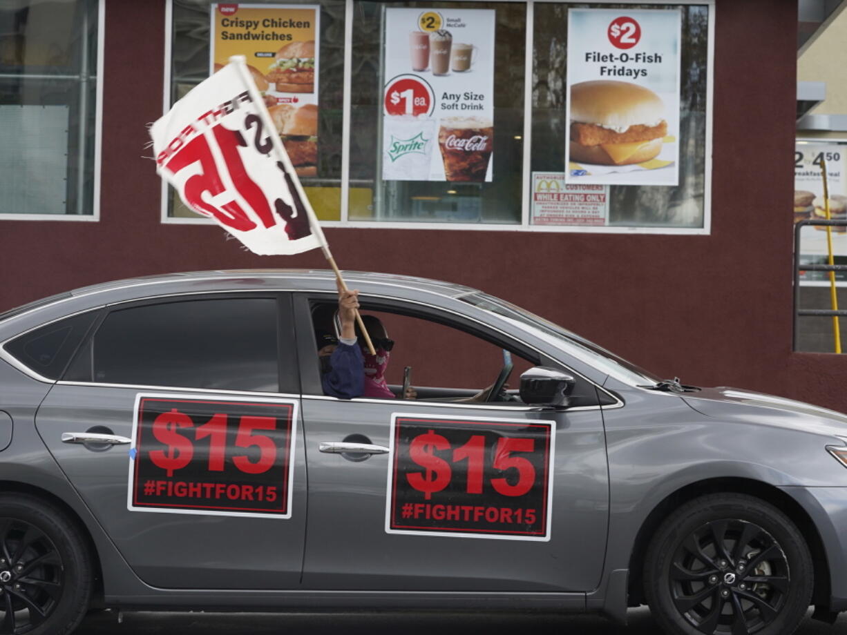 FILE - Fast-food workers drive though a McDonald's restaurant demanding a for a $15 hourly minimum wage in East Los Angeles Friday, March 12, 2021. Minimum wage increases, animal protections, police accountability, cutting and increasing taxes are all part of a series of new laws taking effect across the country on Saturday, the first day of 2022.