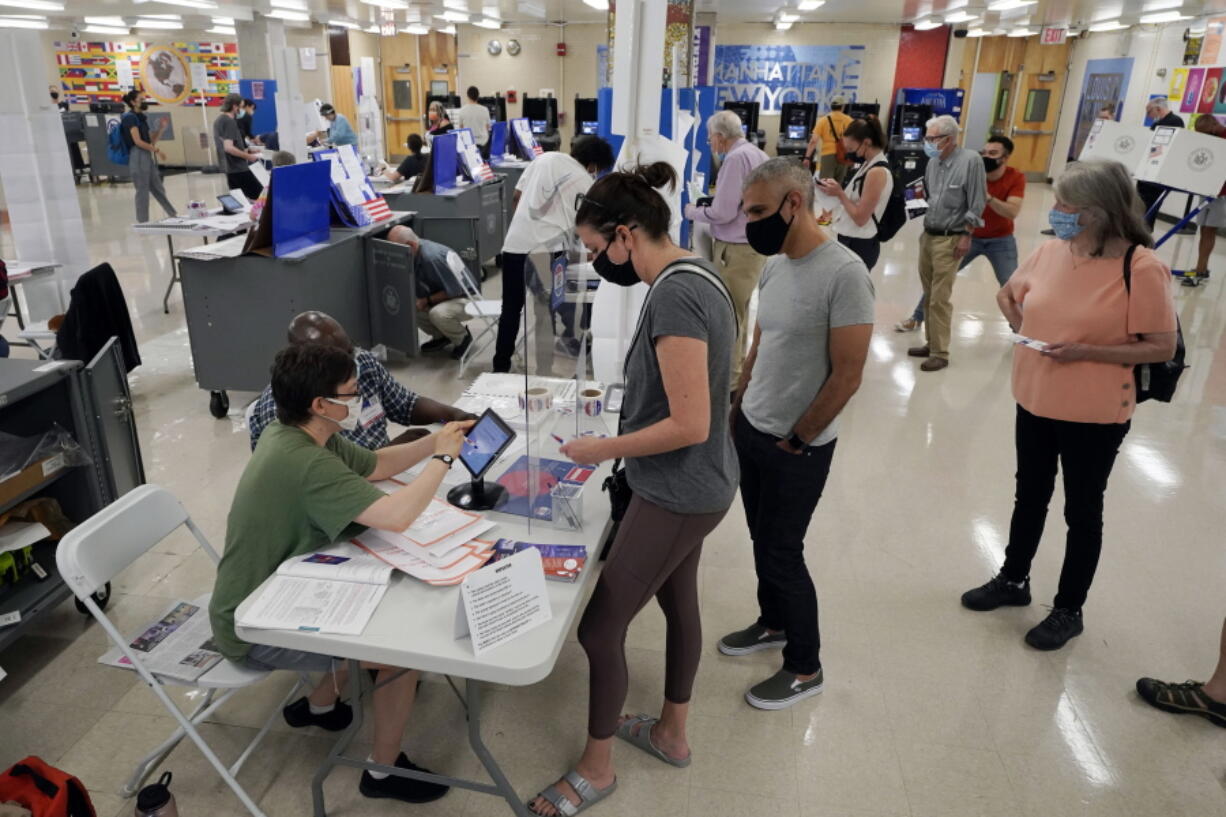 FILE - Voters sign in at Frank McCourt High School for New York's party primaries, June 22, 2021, in New York. New York City, long a beacon for immigrants, is on the cusp of becoming the largest place in the U.S. to give noncitizens the right to vote. Legally documented, voting-age noncitizens, who comprise nearly one in 10 of the city's 8.8 million inhabitants, would be allowed to cast votes in elections to pick the mayor, City Council members and other municipal officeholders under a bill nearing approval.