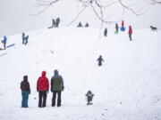 People enjoy Kite Hill in the snow at Gas Works Park Sunday, Dec. 26, 2021, in Seattle. Snow is blanketing parts of the Pacific Northwest because of unusually cold temperatures.  Seattle got between 3 and 5 inches of snow as of Sunday morning.