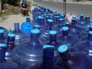 A boy sits beside water containers as residents line up for water as pipelines and electricity were damaged due to Typhoon Rai in Cebu province, central Philippines on Monday Dec. 20, 2021. The death toll in the strongest typhoon to batter the Philippines this year continues to rise and the governor of an island province especially hard-hit by Typhoon Rai said there may be even greater devastation that has yet to be reported.