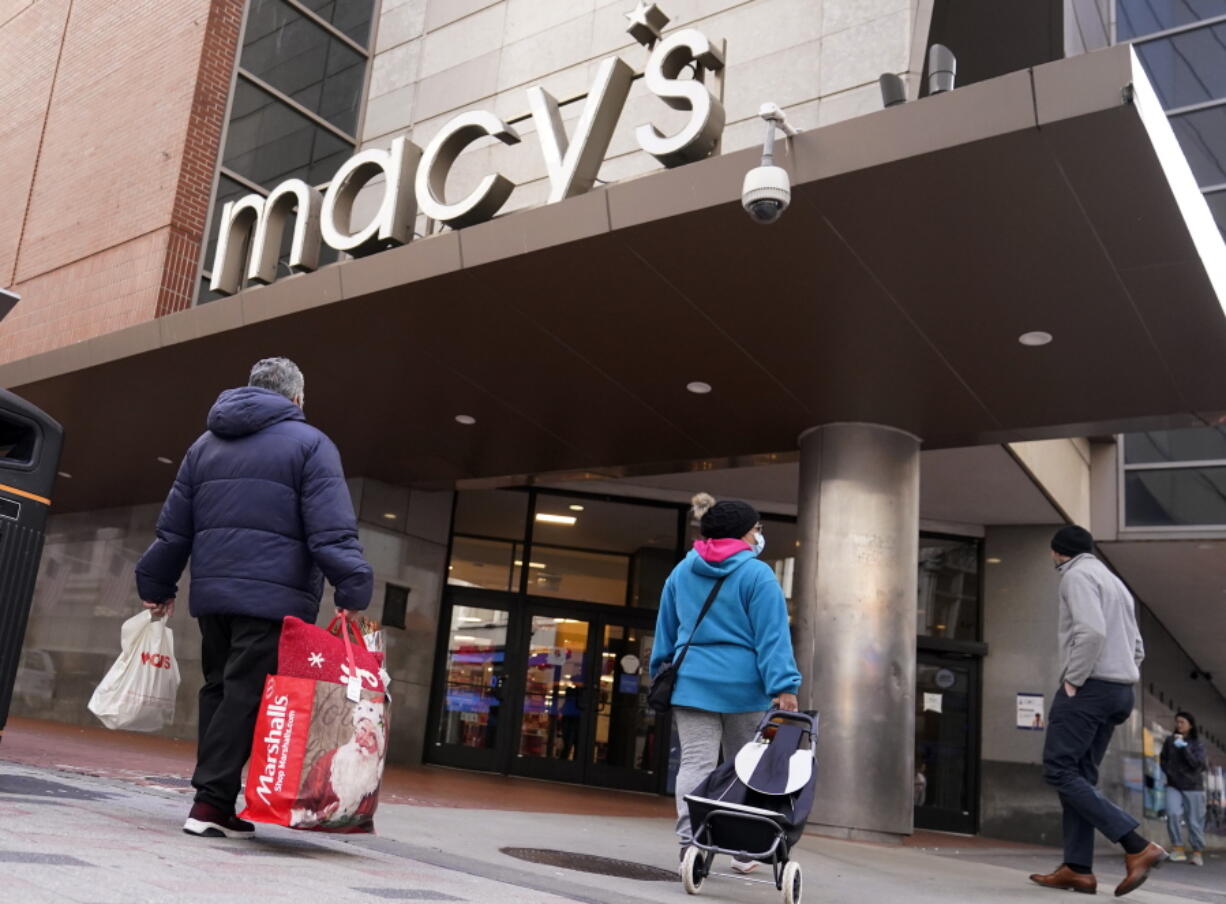 FILE - Shoppers walk to the Macy's store in the Downtown Crossing district, Wednesday, Nov. 17, 2021, in Boston.  Americans slowed their spending in November from October but  they  showed another month of resilience against higher prices and shortages in stores.