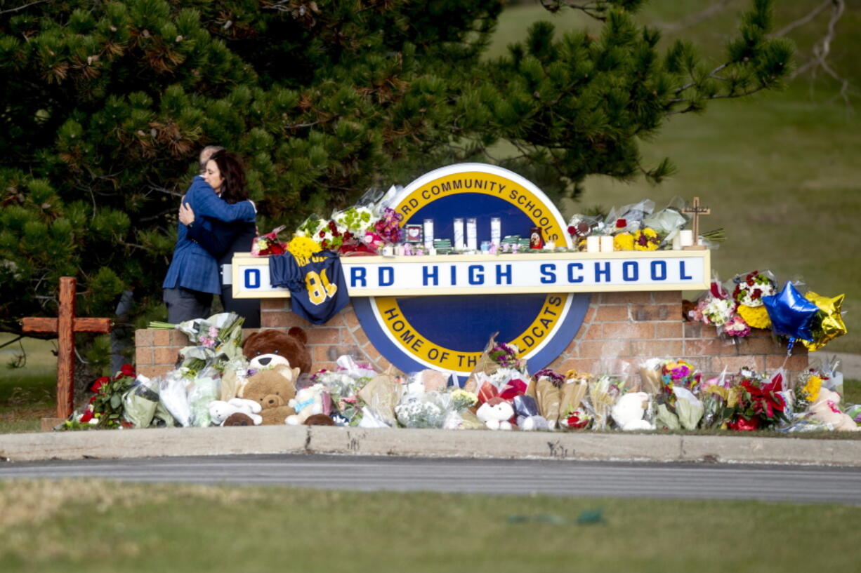 Gov. Gretchen Whitmer embraces Oakland County Executive Dave Coulter as the two leave flowers and pay their respects Thursday morning, Dec. 2, 2021 at Oxford High School in Oxford, Mich.