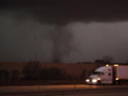 FILE- A tornado approaches Interstate 80 near Atlantic, Iowa, as a semi truck rolls eastward on Wednesday, Dec. 15, 2021. The National Weather Service has declared the series of thunderstorms and tornadoes that swept across the Great Plains and upper Midwest on Dec. 15 as a serial derecho, a rare event featuring a very lengthy and wide line of storms. The service said it was the first-ever serial derecho in December in the U.S.