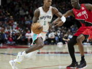 San Antonio Spurs guard Lonnie Walker IV, left, dribbles past Portland Trail Blazers forward Tony Snell during the first half of an NBA basketball game in Portland, Ore., Thursday, Dec. 2, 2021.