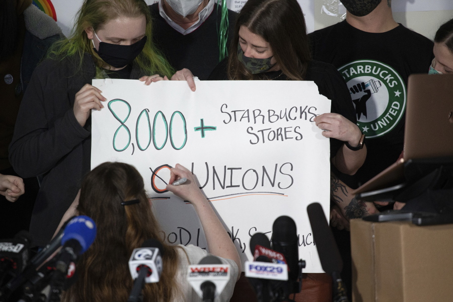 Starbucks employees alter a campaign sign during a press conference after their union-election viewing party Thursday, Dec. 9, 2021, in Buffalo, N.Y. Starbucks workers at a store in Buffalo, voted to unionize on Thursday, a first for the 50-year-old coffee retailer in the U.S. and the latest sign that the labor movement is stirring after decades of decline.