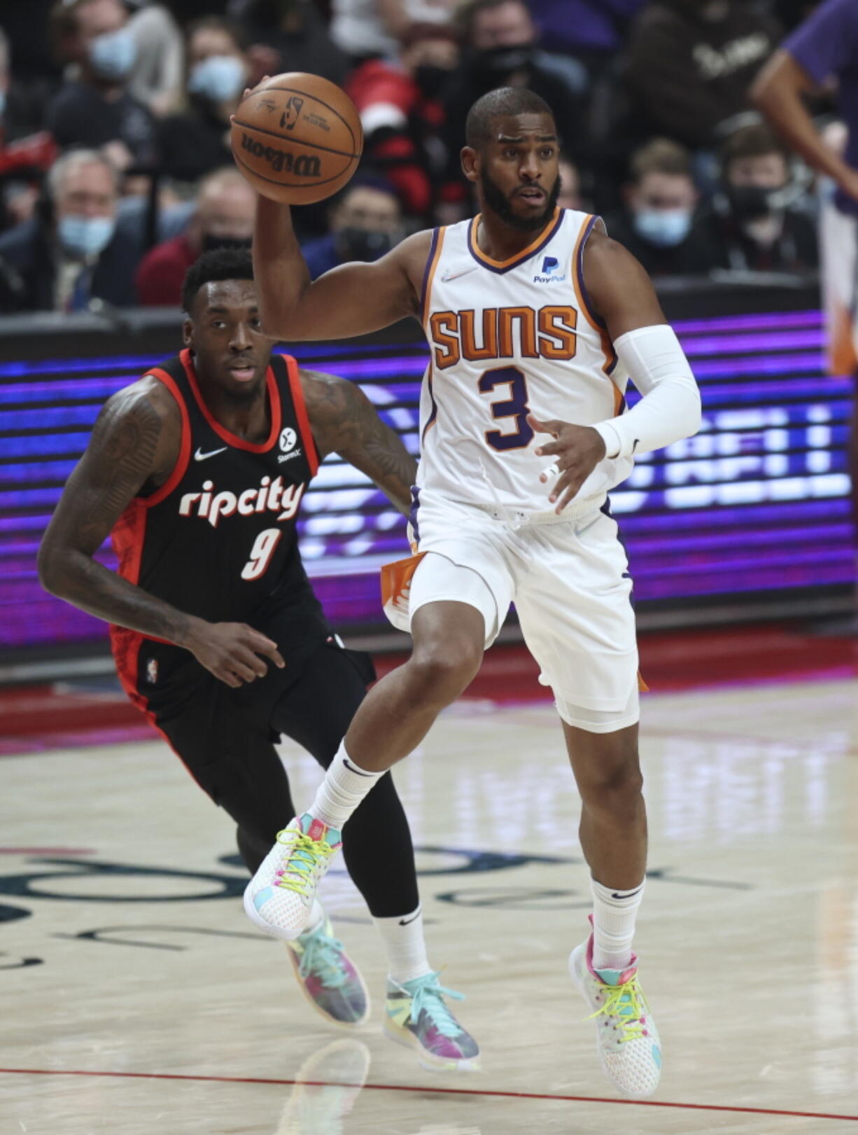 Phoenix Suns guard Chris Paul, right, passes the ball as Portland Trail Blazers forward Nassir Little, left, defends during the first half of an NBA basketball game in Portland, Ore., Tuesday, Dec. 14, 2021.