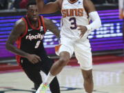 Phoenix Suns guard Chris Paul, right, passes the ball as Portland Trail Blazers forward Nassir Little, left, defends during the first half of an NBA basketball game in Portland, Ore., Tuesday, Dec. 14, 2021.