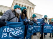 Abortion rights advocates hold signs that read "Abortion is Essential" as they demonstrate in front of the U.S. Supreme Court, Wednesday, Dec. 1, 2021, in Washington, as the court hears arguments in a case from Mississippi, where a 2018 law would ban abortions after 15 weeks of pregnancy, well before viability.