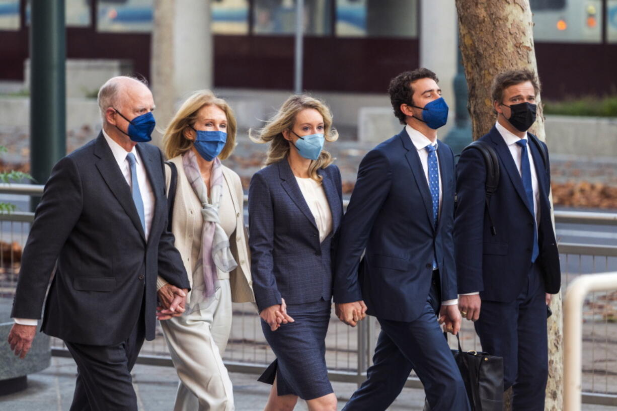 Elizabeth Holmes, center, walks into federal court in San Jose, Calif., Friday, Dec. 17, 2021. The lawyers for the opposing sides in the trial of former Theranos CEO are expected to wrap up their closing arguments Friday, paving the way for a jury to begin their deliberations over criminal charges accusing her of turning her blood-testing startup into a massive scam.