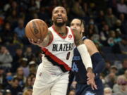 Portland Trail Blazers guard Damian Lillard (0) shoots ahead of Memphis Grizzlies forward Dillon Brooks (24) in the first half of an NBA basketball game Sunday, Dec. 19, 2021, in Memphis, Tenn.