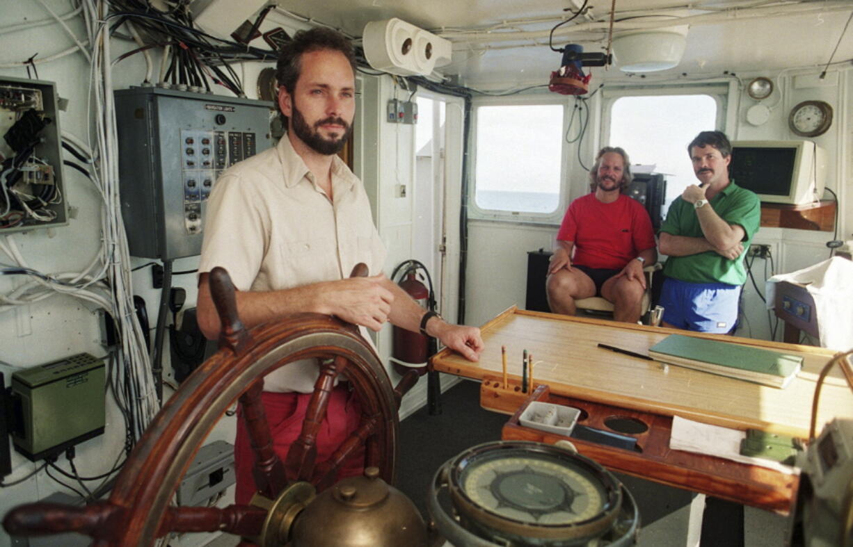 FILE - In this Aug. 29, 1991, file photo, Tommy Thompson stands at the helm of the Arctic Explorer as Bob Evans, center, and Barry Schatz look on in Norfolk, Va. Thompson, a former deep-sea treasure hunter, is about to mark his fifth year in jail for refusing to disclose the whereabouts of 500 missing gold coins found in the historic shipwreck of the S.S. Central America, known as the Ship of Gold.