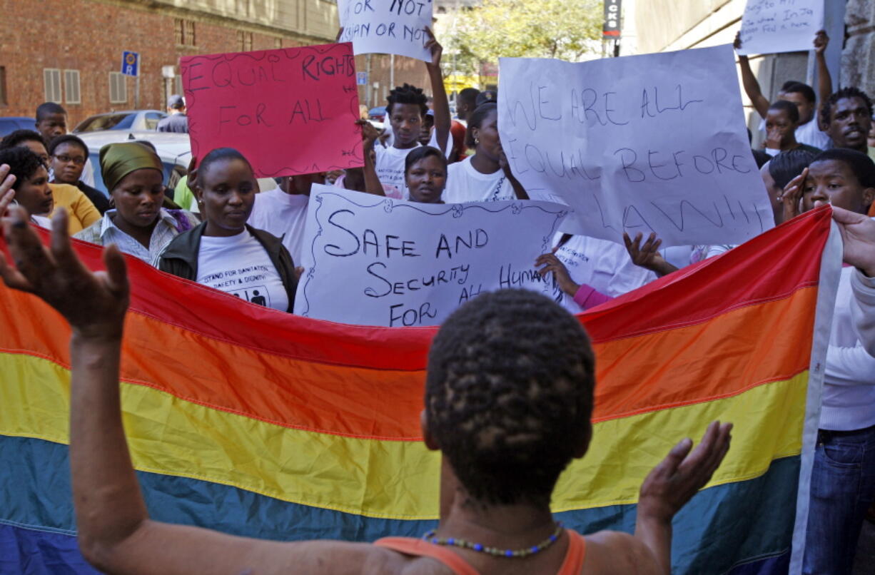 FILE - Women in Cape Town, South Africa, protest a sentence given to two men under Malawi's anti-gay legislation on May 20, 2010. Desmond Tutu is being remembered for his passionate advocacy on behalf of LGBTQ people as well as his fight for racial justice. But the South African archbishop's campaign against homophobia had limited impact in the rest of Africa.