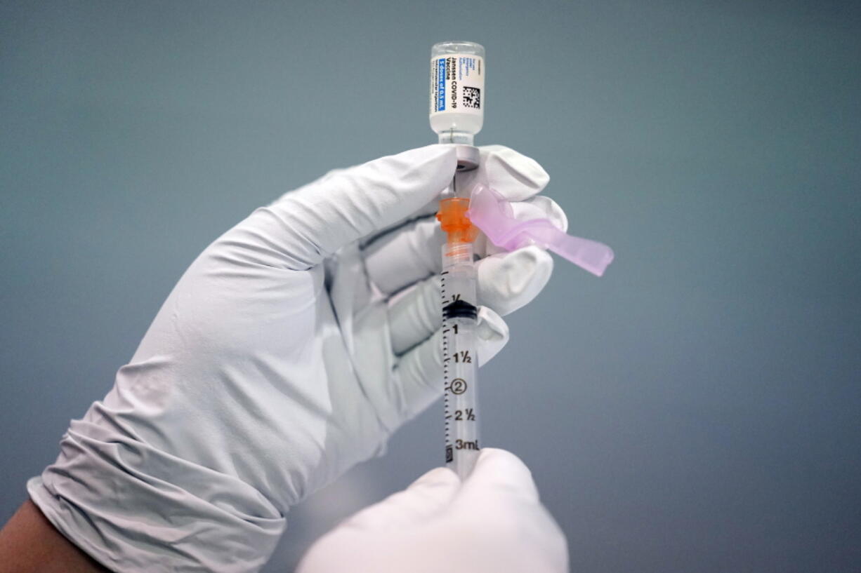 FILE - A member of the Philadelphia Fire Department prepares a dose of the Johnson & Johnson COVID-19 vaccine at a vaccination site setup in Philadelphia, on March 26, 2021.  A government advisory panel is meeting Thursday, Dec. 16,  to determine if any restrictions are needed to the Johnson & Johnson COVID-19 vaccine because of rare but serious blood clots.